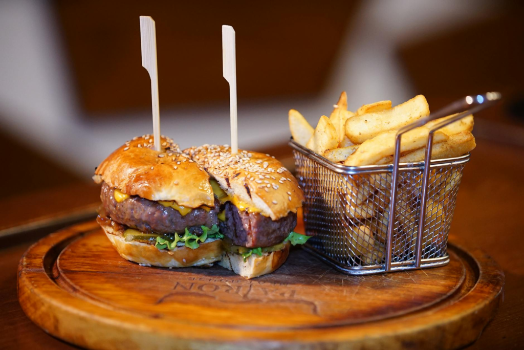A BBQ burger served with sweet potato fries on a wooden platter. — burger combos Las Vegas