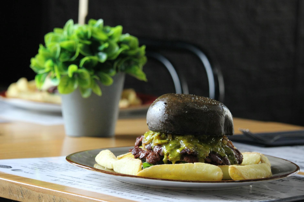 A beautifully plated Umami Burger with unique toppings, set against a vibrant restaurant backdrop. — iconic burgers Las …