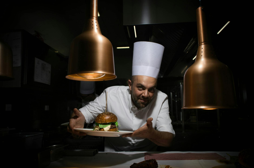 A celebrity chef presenting a gourmet burger at a high-end restaurant. — burger trends Las Vegas 2026