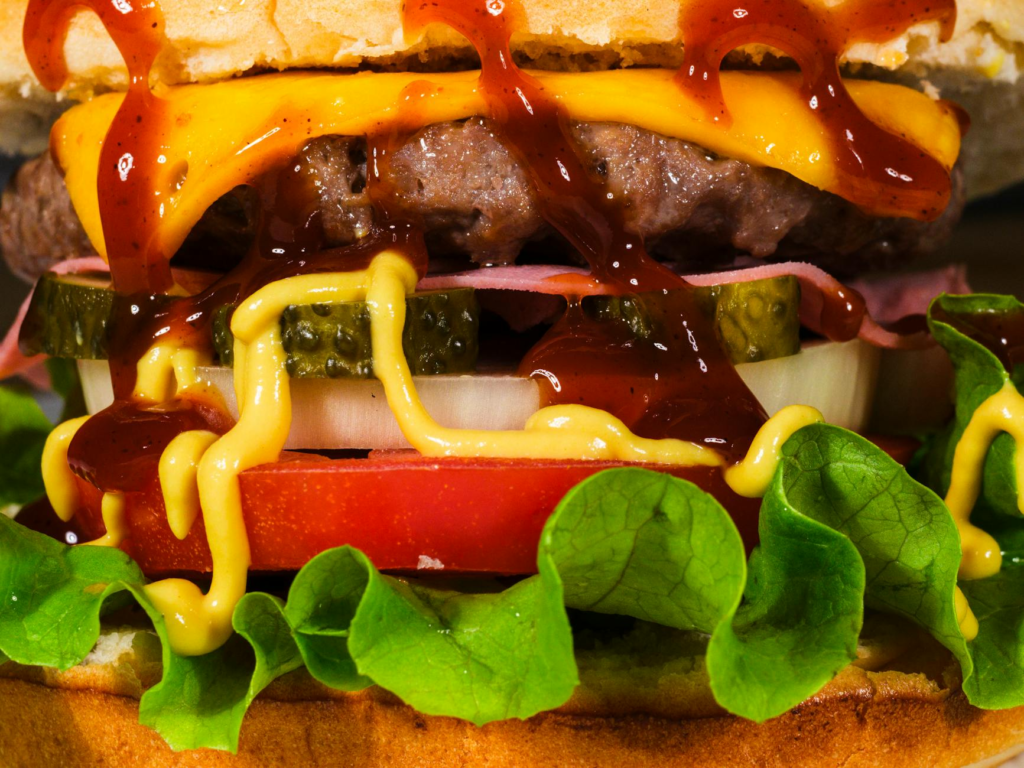 A close-up of a gourmet burger showcasing its layers of toppings and sauces. — burger deals Las Vegas