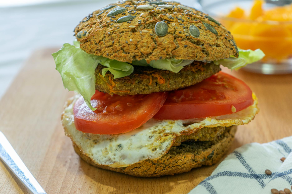 A close-up of a vegan burger with a whole grain bun and colorful toppings, emphasizing plant-based eating. — healthy bur…