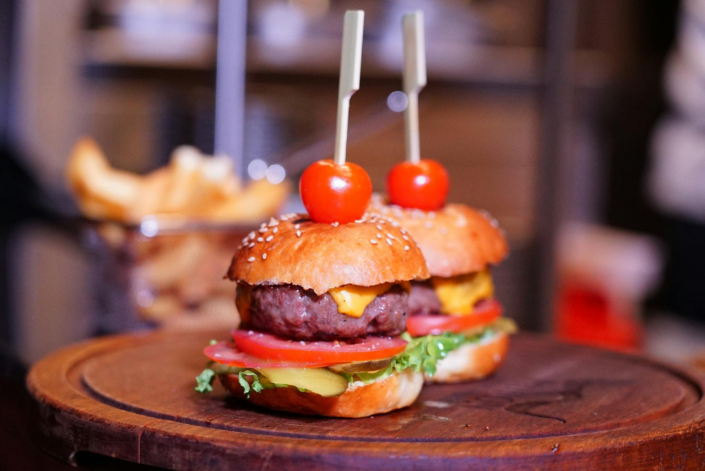 A close-up of cheeseburger sliders topped with lettuce, tomato, and cheese. — cheeseburger sliders toppings