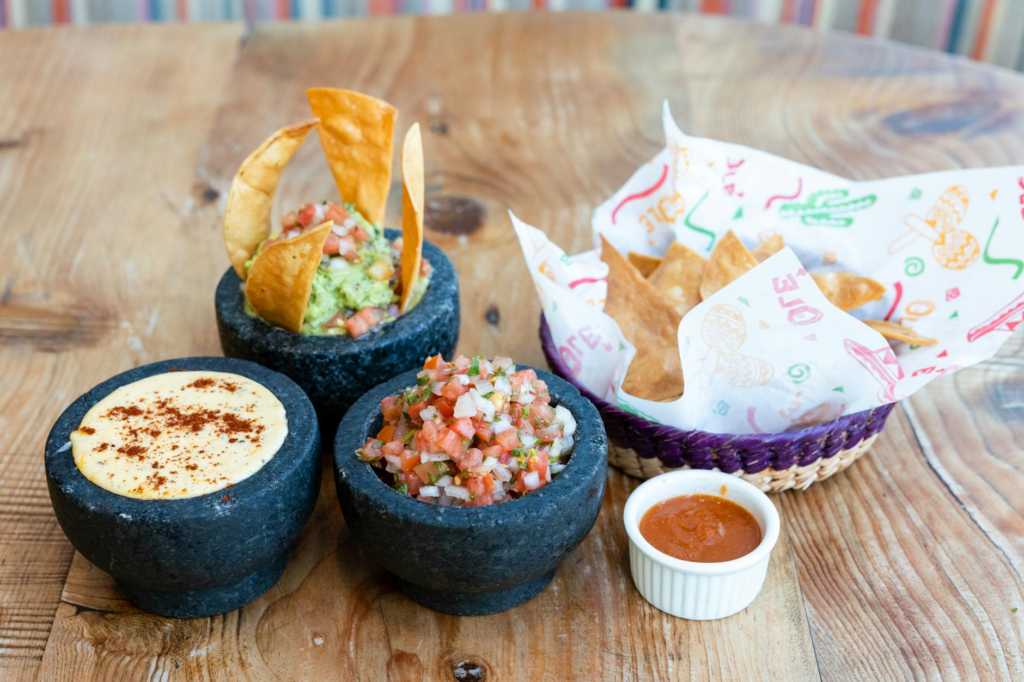A close-up of dips like guacamole and queso served alongside cheeseburger sliders. — side dishes for cheeseburger sliders