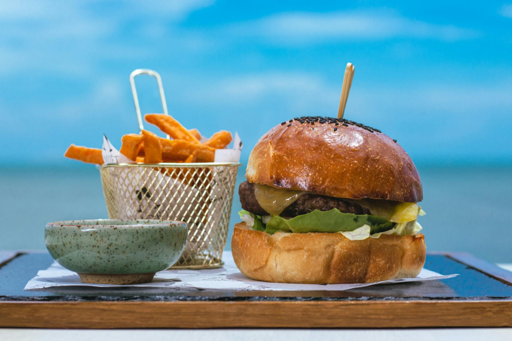 A close-up of gourmet sweet potato fries alongside a classic cheeseburger. — burger side dishes Las Vegas