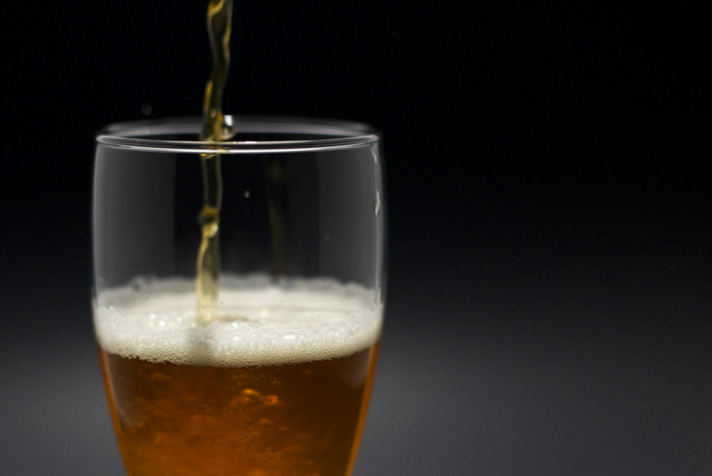 A close-up shot of a craft beer poured next to a slider, highlighting the pairing. — drinks to pair with cheeseburger sl…