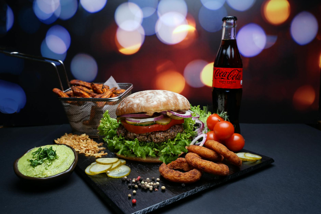A close-up shot of a juicy burger with fresh lettuce, tomato, and a side of onion rings. — late night burgers Las Vegas