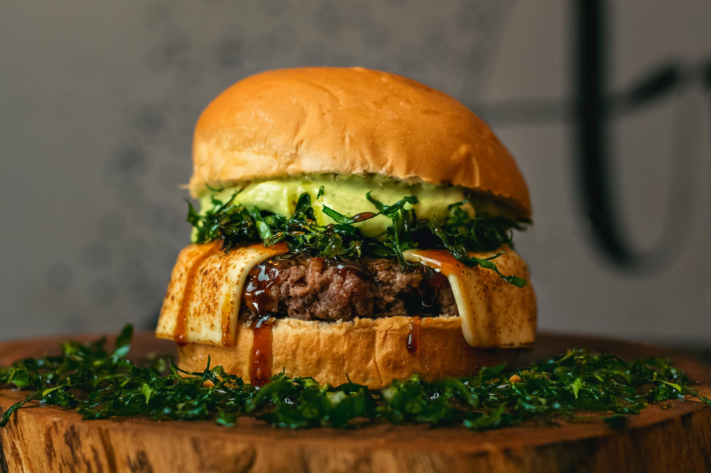 A close-up shot of a juicy plant-based burger with melted vegan cheese and avocado. — vegan burgers Las Vegas
