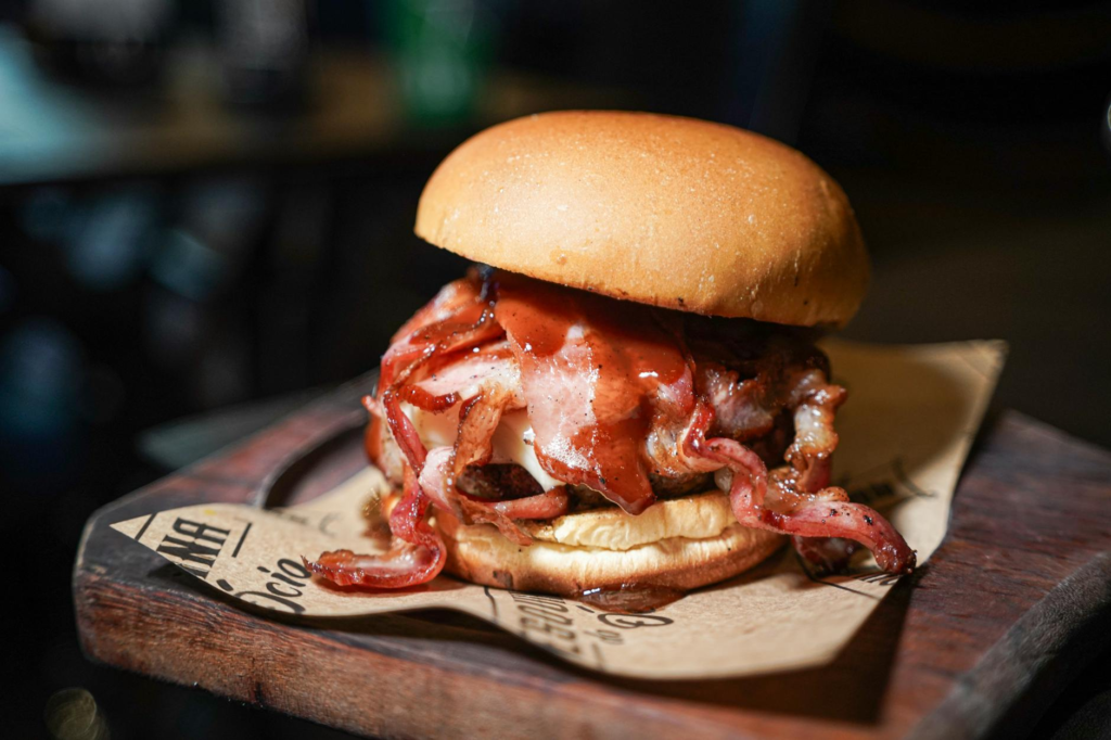 A delicious Merry Maple Bacon Burger glistening with maple syrup. — Holiday Celebration Burgers Las Vegas