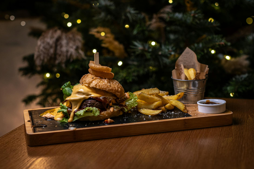 A festive burger topped with cranberry sauce and brie cheese on a rustic wooden table. — Holiday Burger Toppings Las Vegas