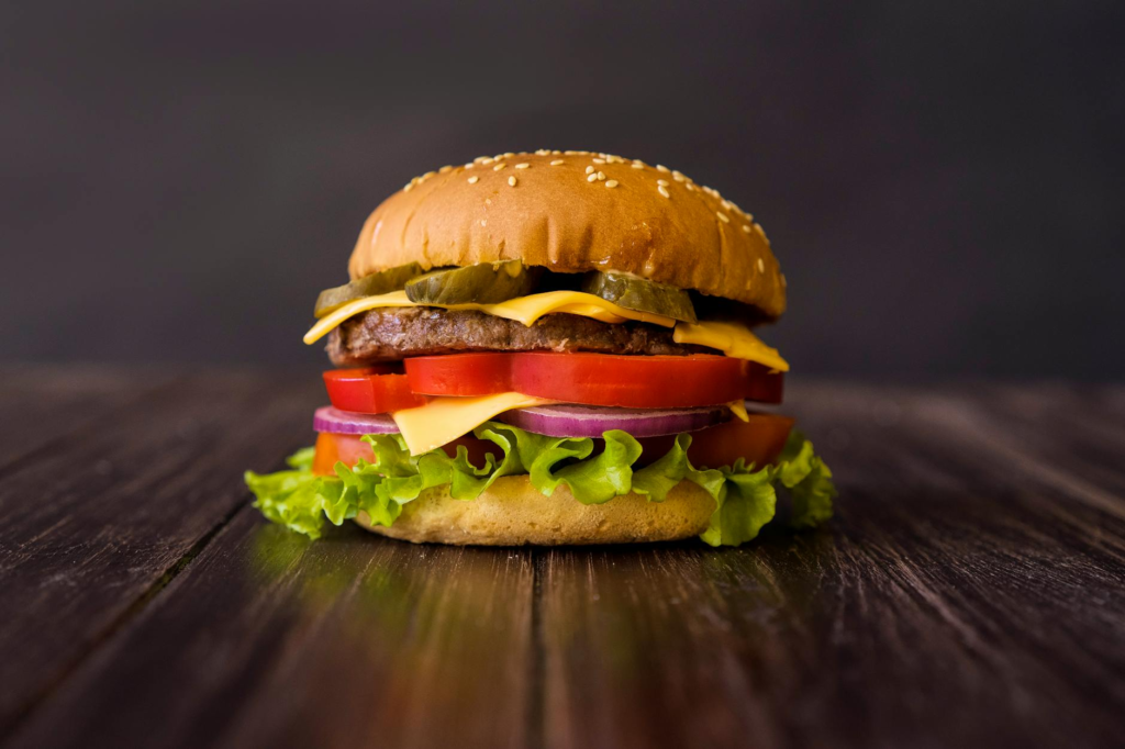 A mouth-watering classic cheeseburger with melted cheese and fresh toppings on a wooden table. — classic cheeseburgers L…