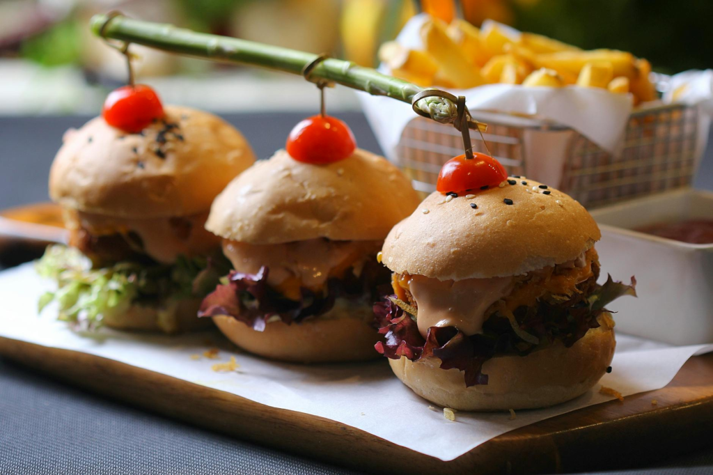 A mouth-watering plate of cheeseburger sliders with various toppings. — cheeseburger sliders vs burgers