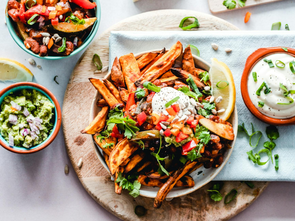A vibrant plate of a vegan burger topped with fresh vegetables and a side of sweet potato fries. — vegan burgers Las Vegas