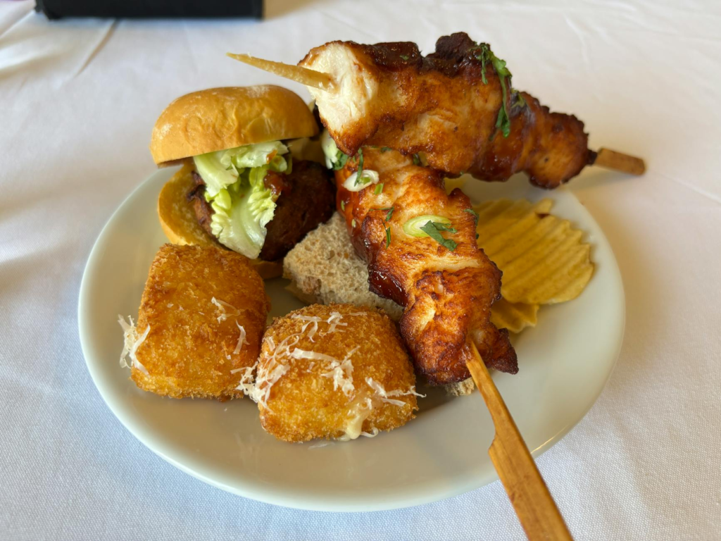 A vibrant plate of cheeseburger sliders with a variety of drinks in the background. — drinks to pair with cheeseburger s…