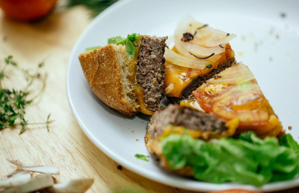 An artistic shot of a burger cut in half, revealing the layers of colorful ingredients inside. — Instagrammable Holiday …