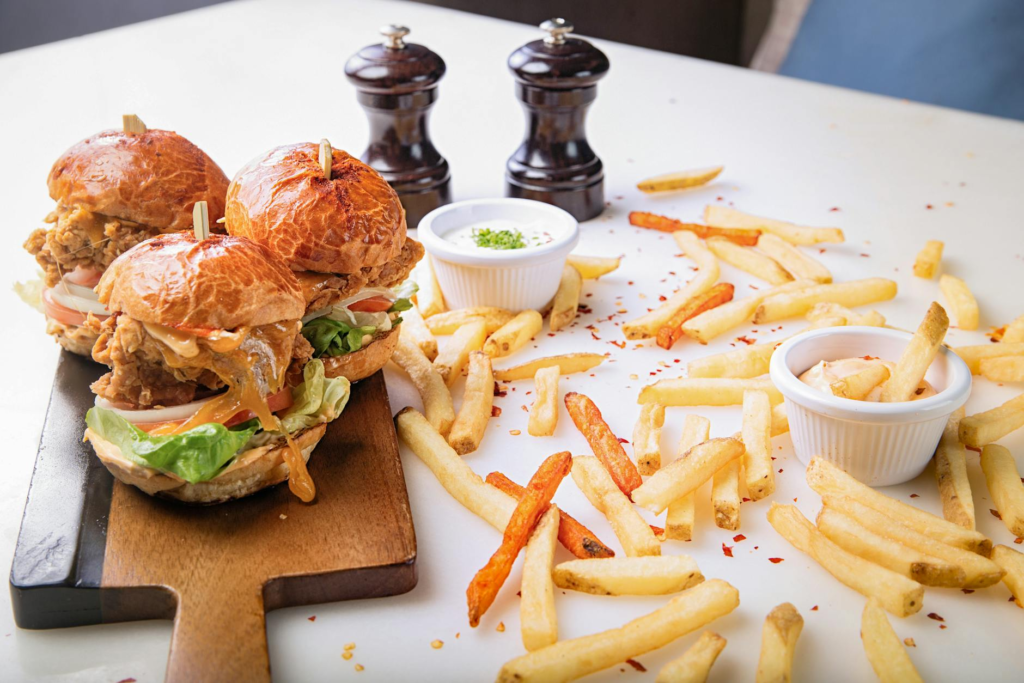Close-up of assembled sliders with various toppings and condiments. — DIY cheeseburger slider kits