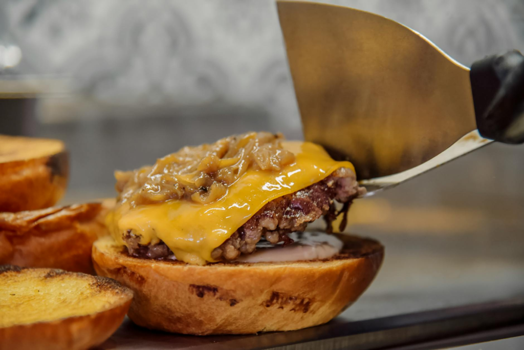 Image showcasing the assembly of a gourmet Las Vegas-style burger with toppings. — burger making process Las Vegas