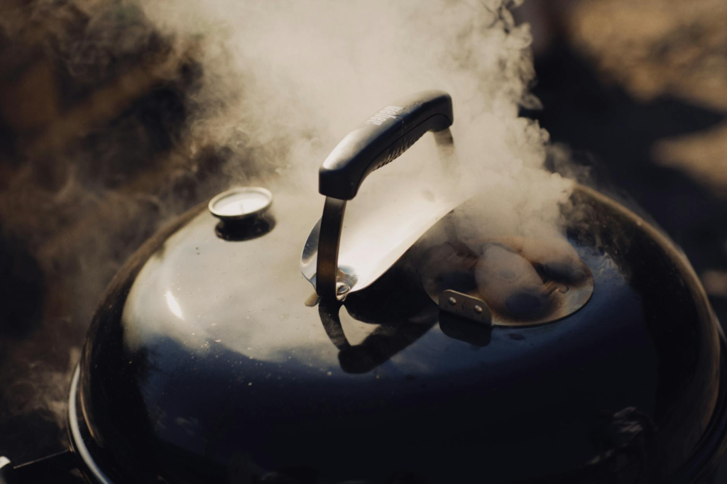 Sliders grilling on a barbecue with smoke rising. — cheeseburger sliders recipe