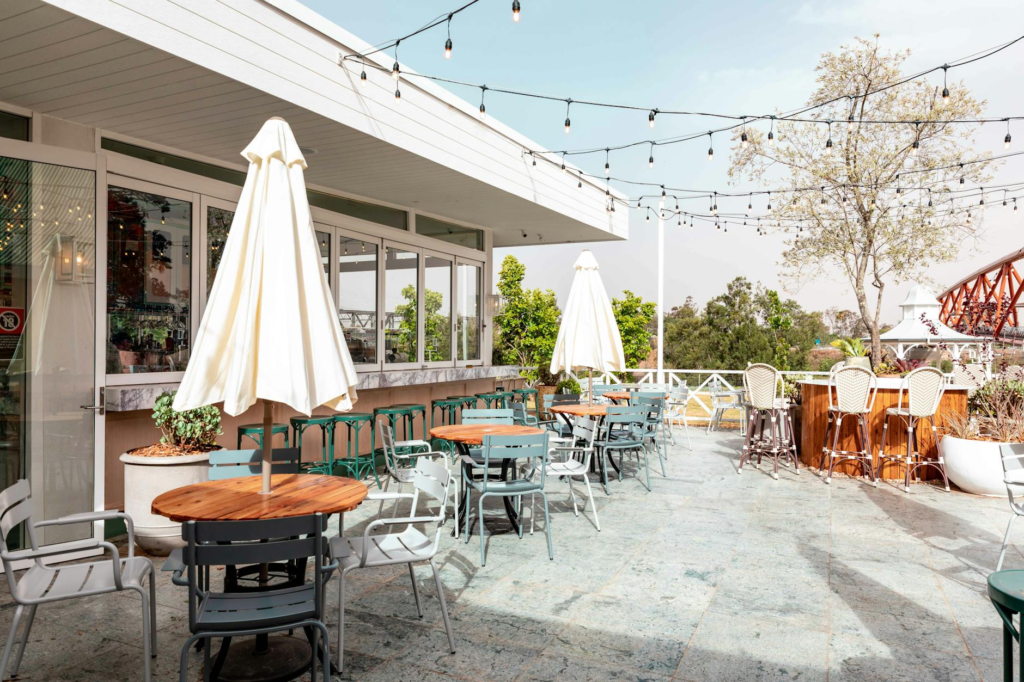 A lively outdoor patio scene at Yardbird Southern Table & Bar, showcasing happy diners and beautiful views. — burger…
