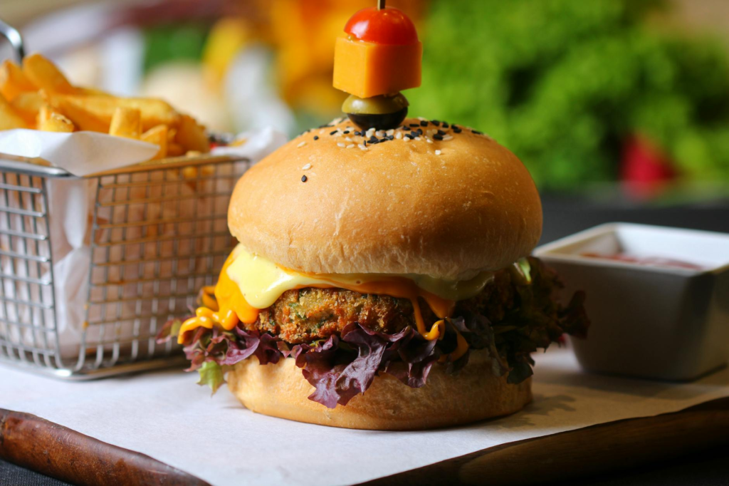 A mouthwatering vegan burger topped with fresh vegetables and sauces on a wooden table. — best vegan burgers Las Vegas