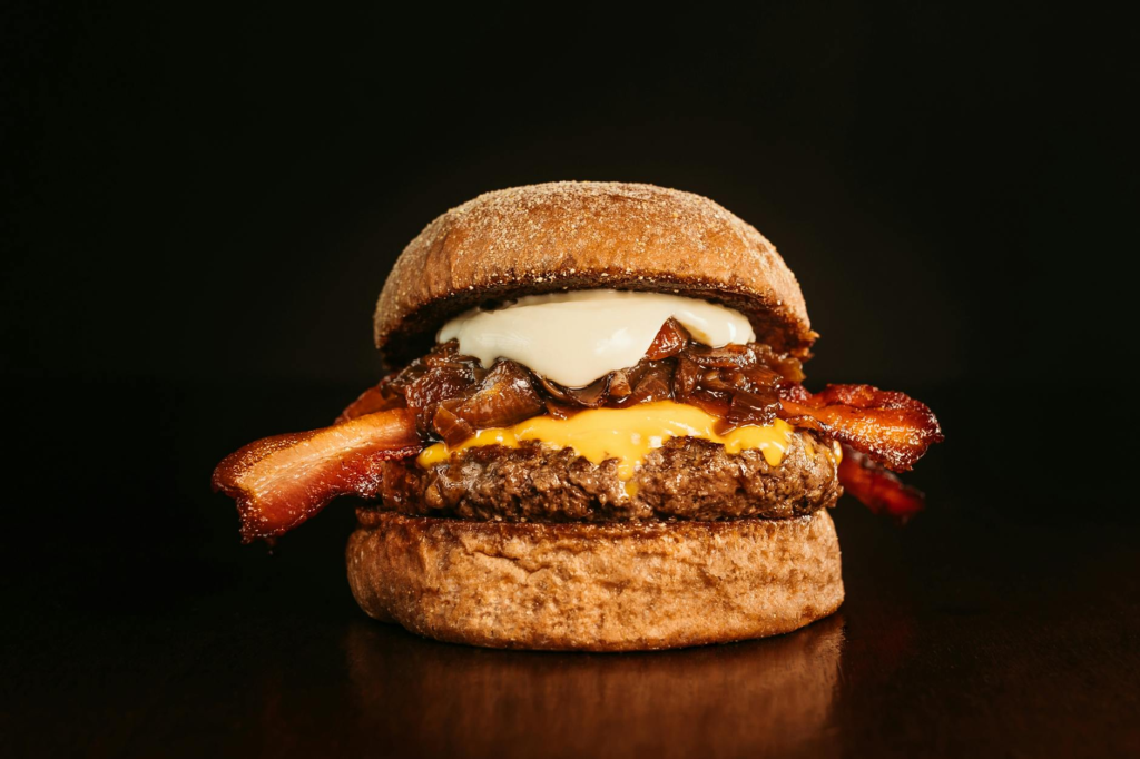 An inviting shot of a gourmet burger at Gordon Ramsay Burger with the Las Vegas Strip in the background. — burgers with …