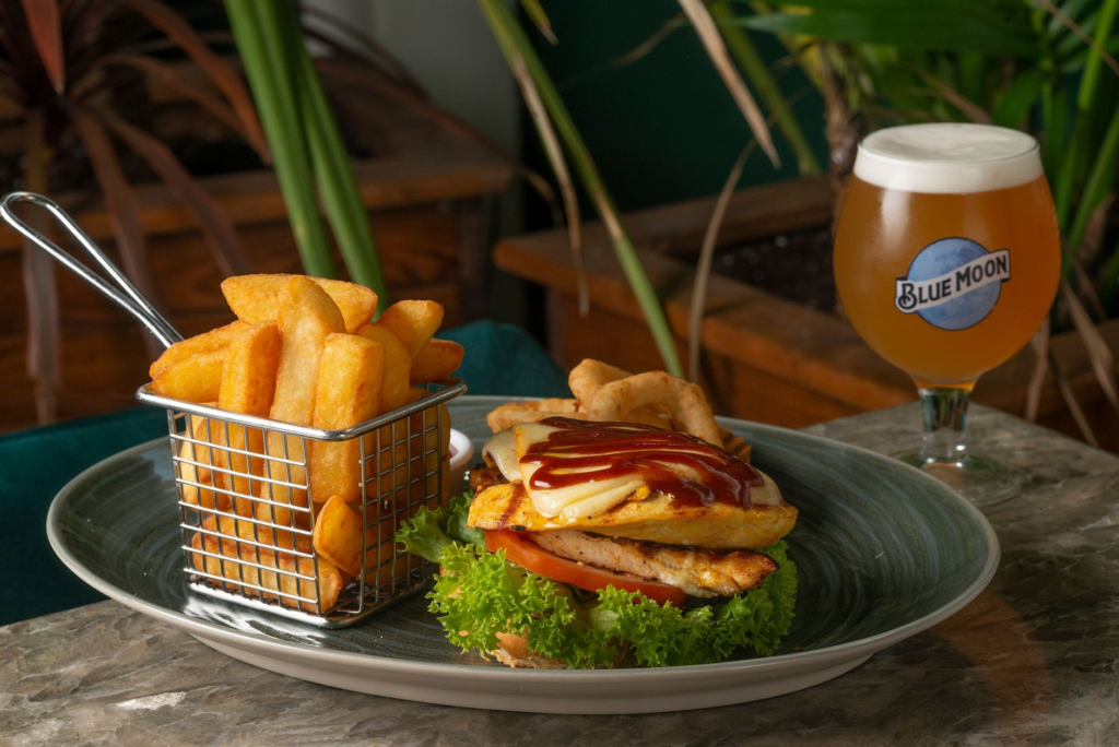 A beautifully plated burger next to a matching beer glass on a rustic table. — burgers and beer Las Vegas