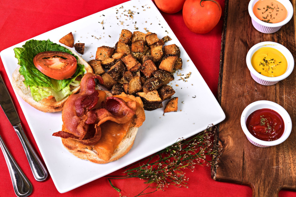 A beautifully presented gourmet burger on a plate, garnished with fries and dipping sauces. — juiciest burgers Las Vegas…