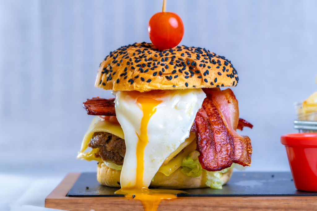 A breakfast burger stacked with bacon, eggs, and avocado on a toasted bun. — unique burgers in Las Vegas