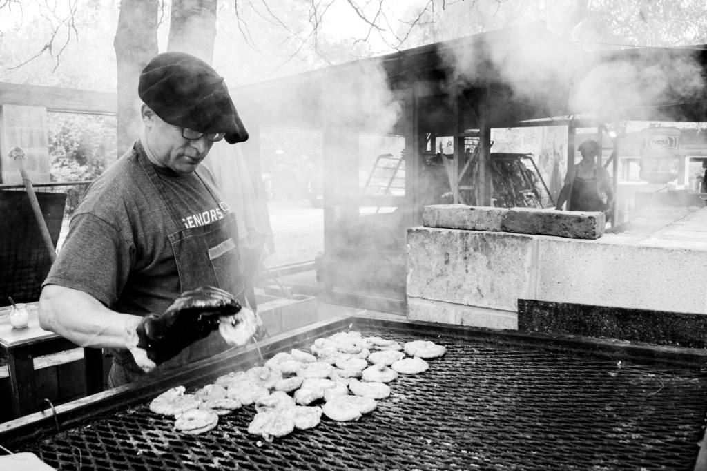 A chef grilling chicken patties on an outdoor grill with vibrant vegetables. — chicken burgers las vegas