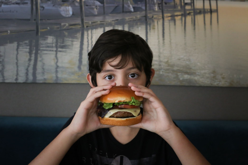 A child enjoying a colorful kids menu burger with fun toppings. — family-friendly burgers Las Vegas