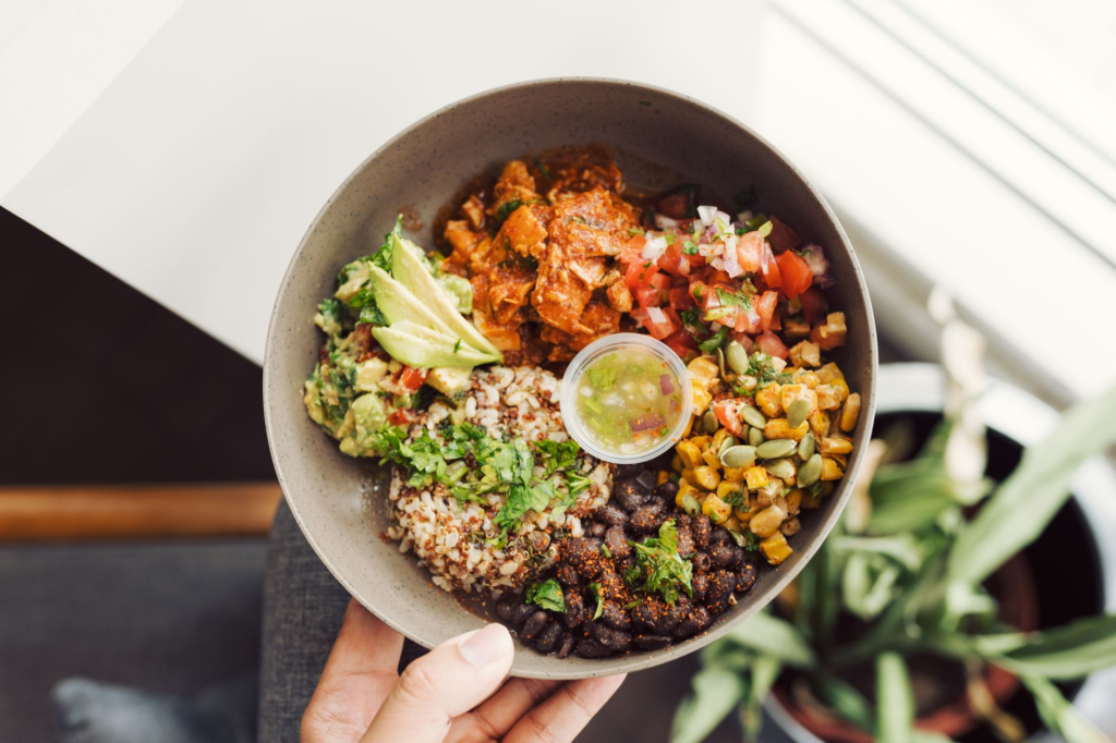 A close-up of a delicious black bean burger topped with avocado and salsa, showcasing the textures and colors. — vegan b…