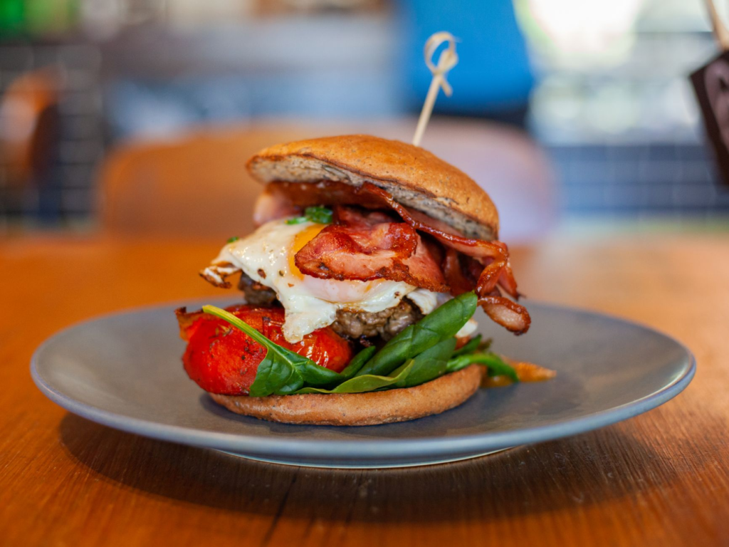 A close-up of a gourmet breakfast burger featuring avocado, bacon, and a perfectly cooked egg. — breakfast burgers las v…