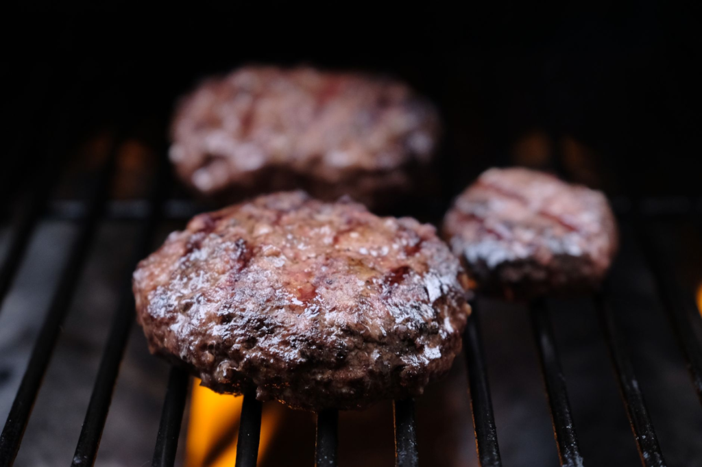 A close-up of a gourmet burger patty sizzling on the grill, showcasing the best gourmet burgers Las Vegas has to offer