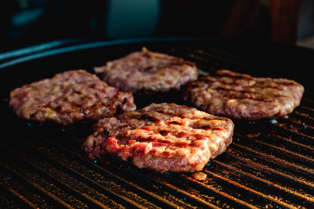 A close-up of a juicy burger being grilled, emphasizing the cooking techniques of a local favorite. — hidden gem burgers…
