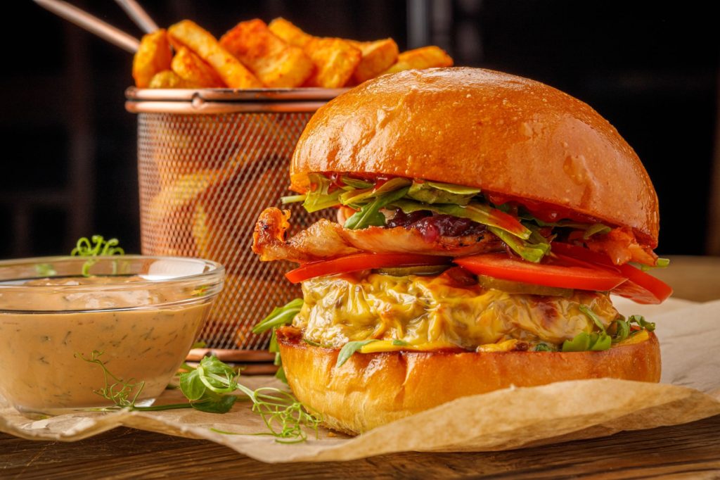 A close-up of a juicy burger topped with fresh ingredients, alongside unique side dishes. — burger and drink pairings La…
