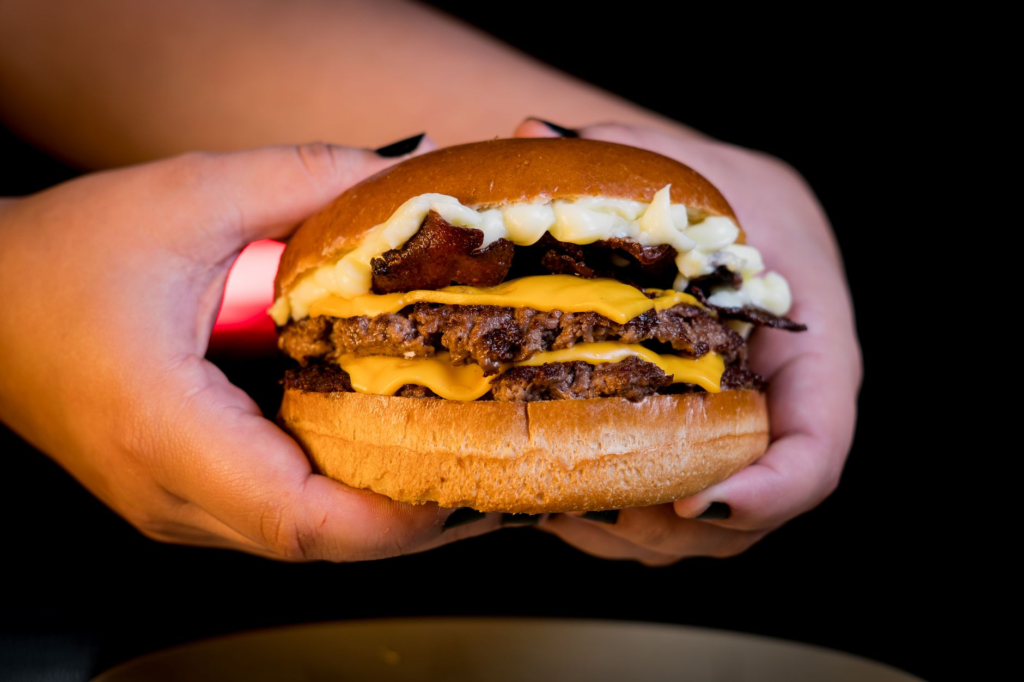 A close-up of a spicy mac and cheese burger dripping with cheese. — unique burgers in Las Vegas