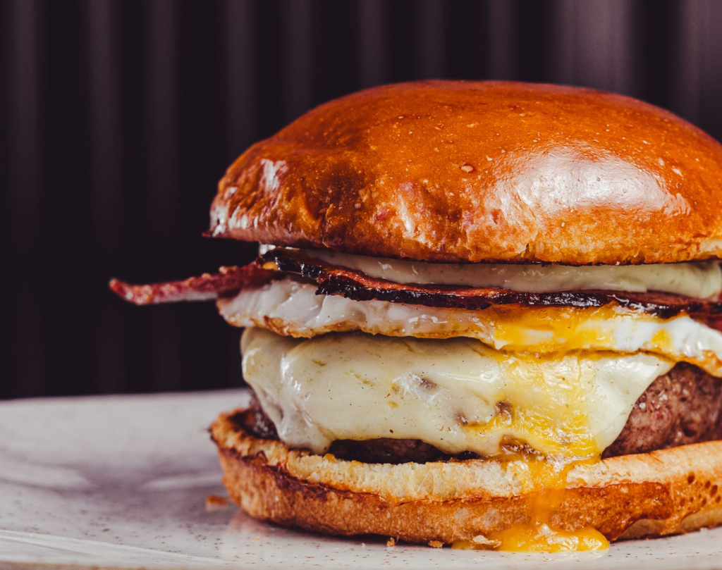 A close-up shot of a burger with melted cheese and fresh ingredients, perfect for food photography. — instagrammable bur…