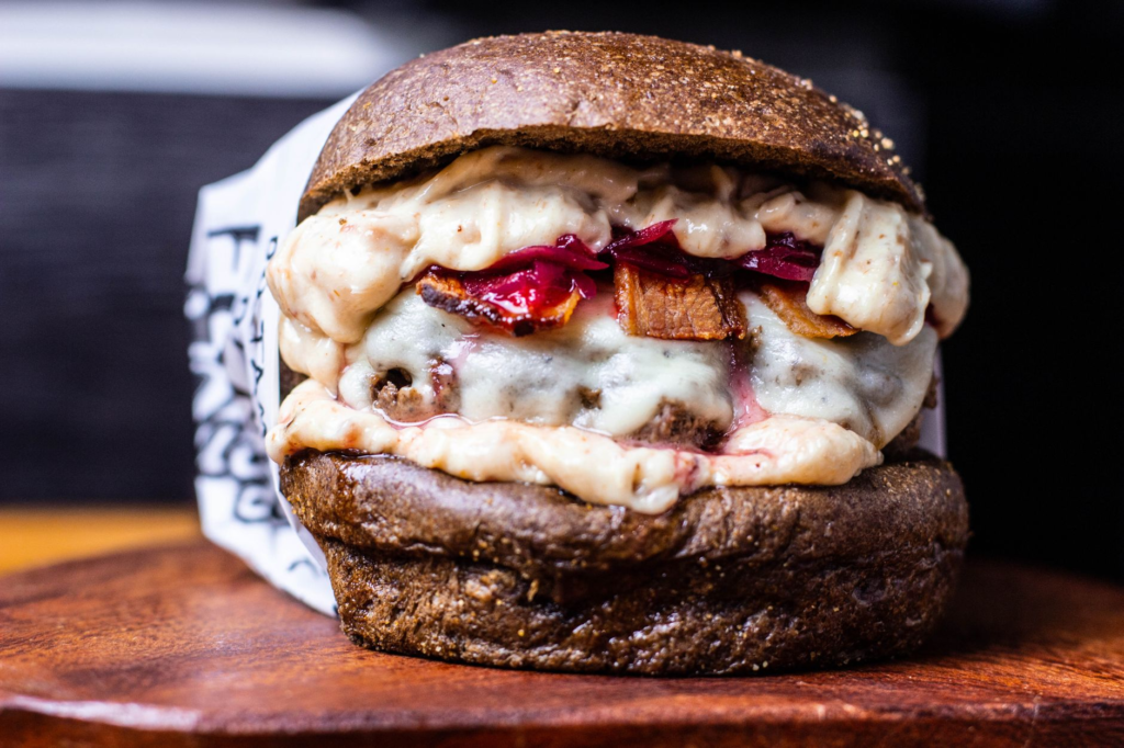 A close-up shot of a gourmet burger showcasing unique toppings and sauces. — best cheeseburgers Las Vegas