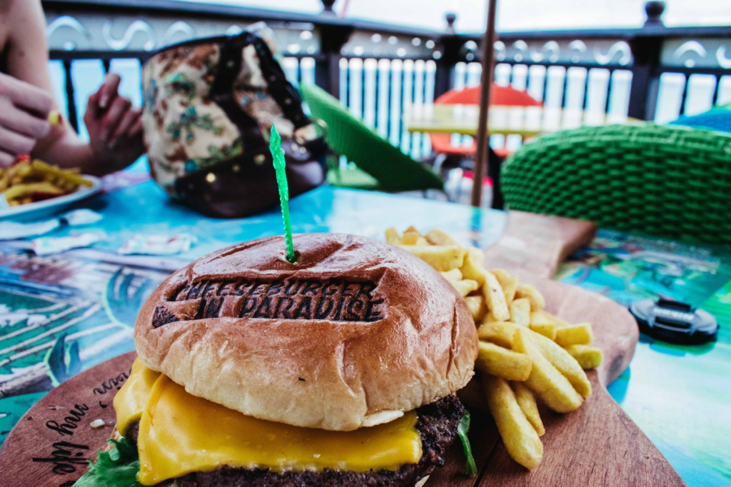 A close-up shot of a signature burger with fries, set against a scenic mountain backdrop. — burgers with a view Las Vegas