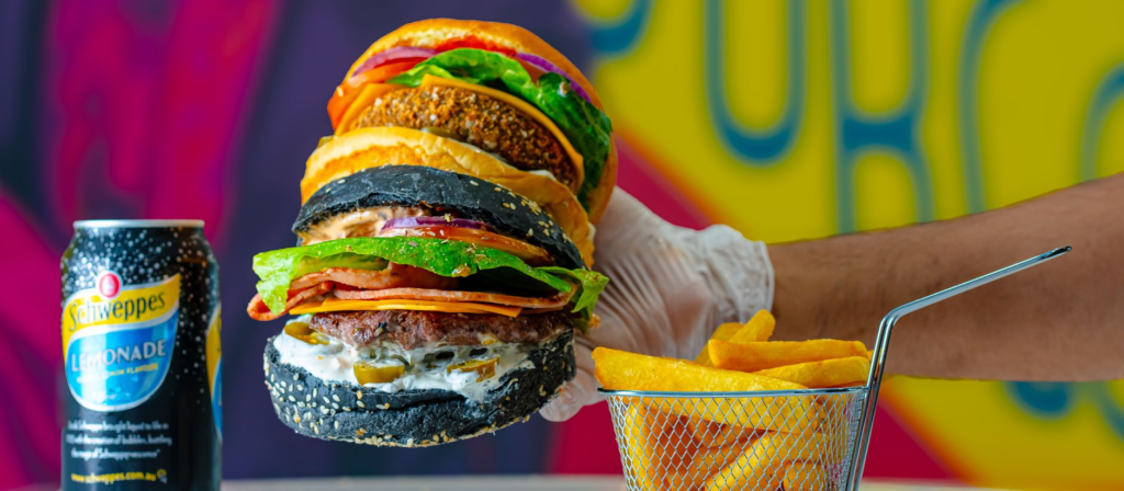 A colorful burger stacked high with toppings, set against a vibrant backdrop. — instagrammable burgers las vegas