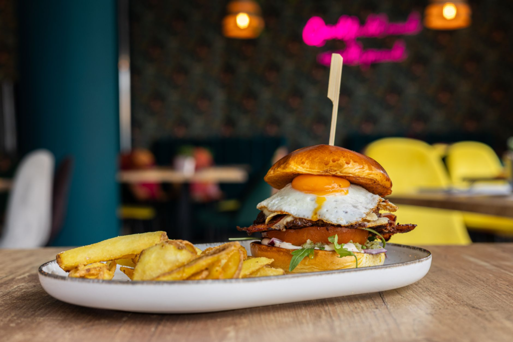 A colorful shot of the Brunch Burger at Therapy, with a sunny-side-up egg and crispy bacon on top. — unique burgers Las …