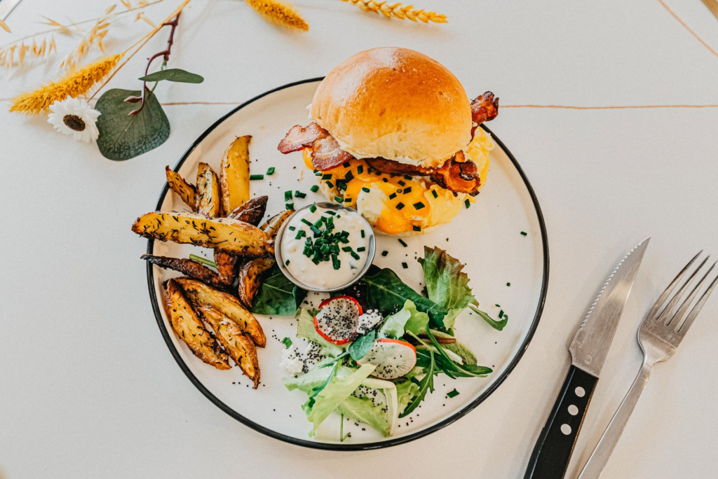 A gourmet burger topped with avocado and bacon, garnished with fresh herbs — best gourmet burgers Las Vegas