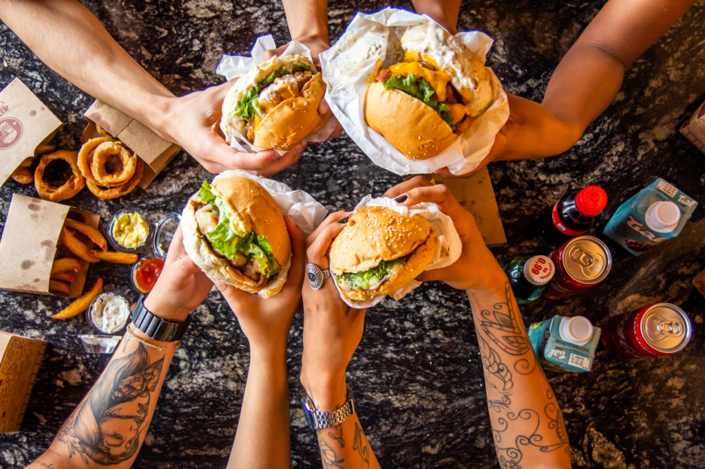 A group of friends participating in a burger challenge, with various spicy burgers on the table. — spicy burgers Las Vegas