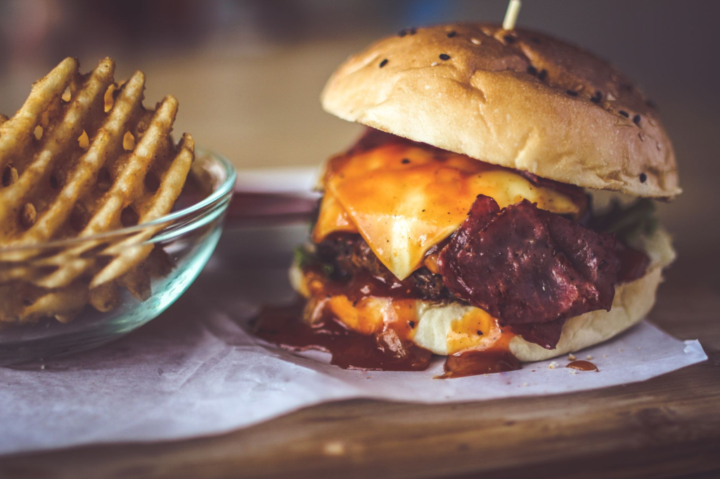 A mouth-watering close-up of a gourmet burger with fries, showcasing the delicious toppings and textures. — burger deals…
