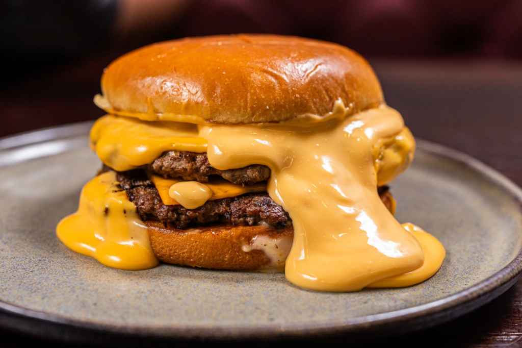 A mouthwatering burger from Gordon Ramsay Burger with melted cheese and toppings — juiciest burgers Las Vegas Strip