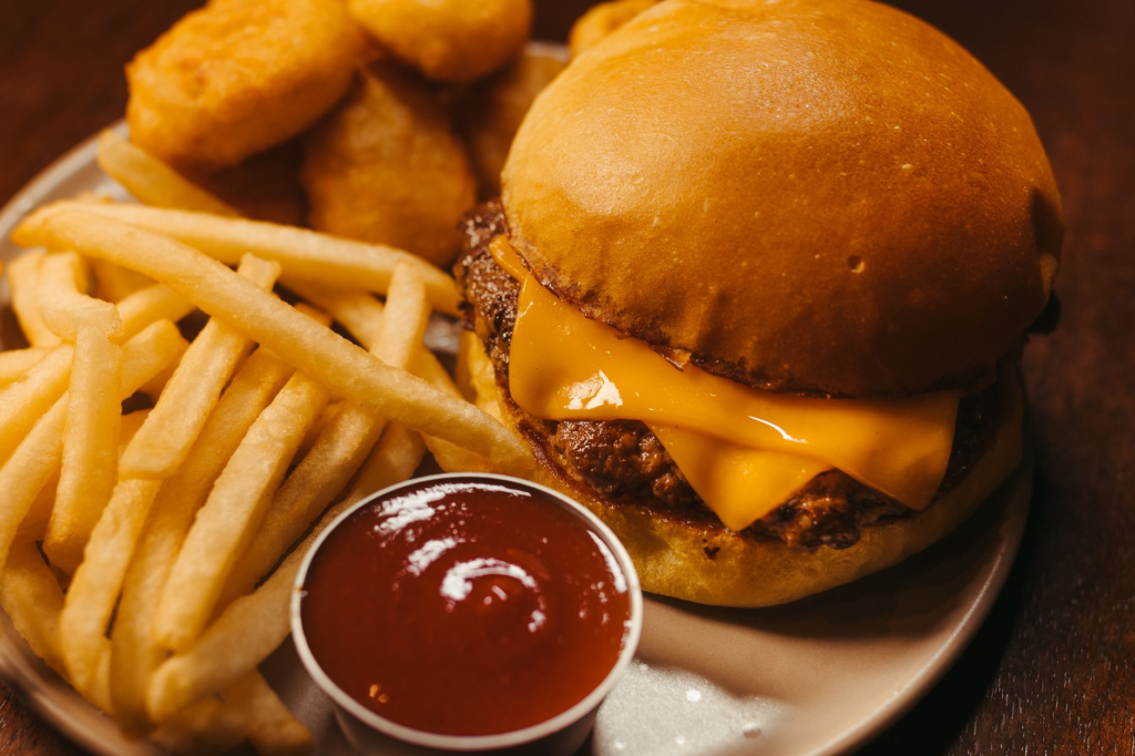 A plate of crispy smash burgers accompanied by fries and dipping sauces. — smash burgers las vegas