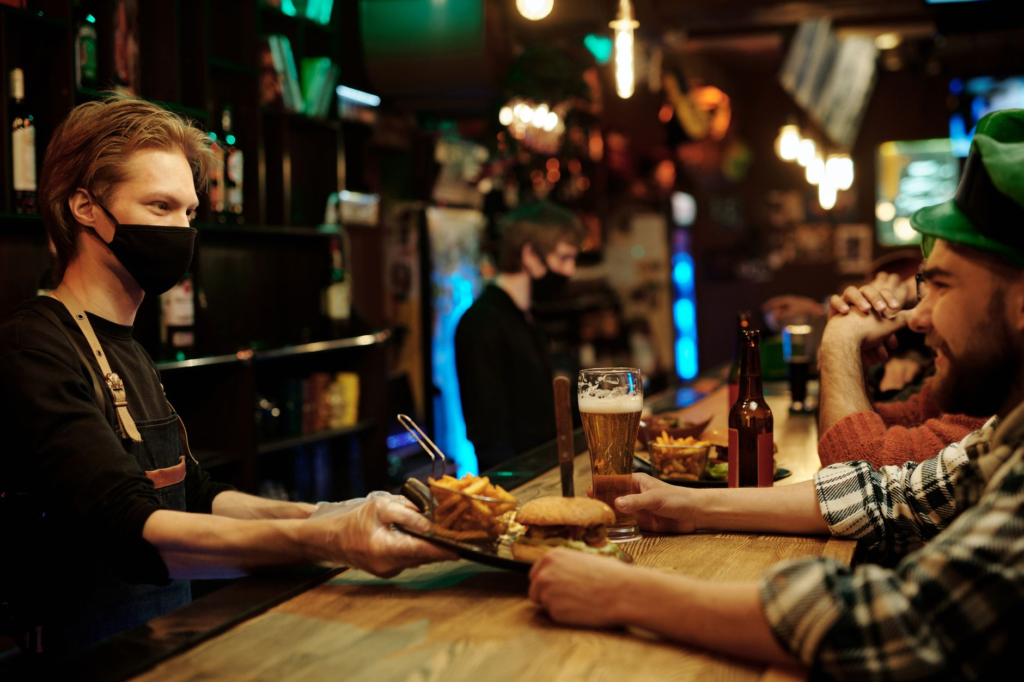 A vibrant scene of a bustling bar during happy hour with patrons enjoying burgers and drinks. — burger deals Las Vegas
