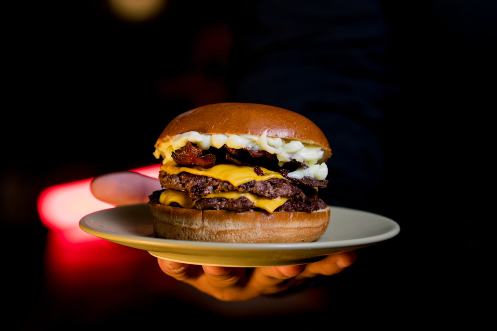 An artistic image of a gourmet burger stacked high with ingredients, showcasing the quality of affordable burgers. — che…