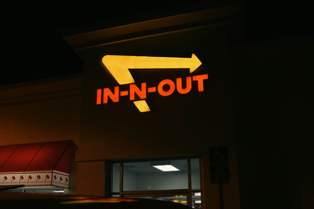 An inviting exterior shot of In-N-Out Burger, highlighting its iconic sign and late-night customers. — late night burger…