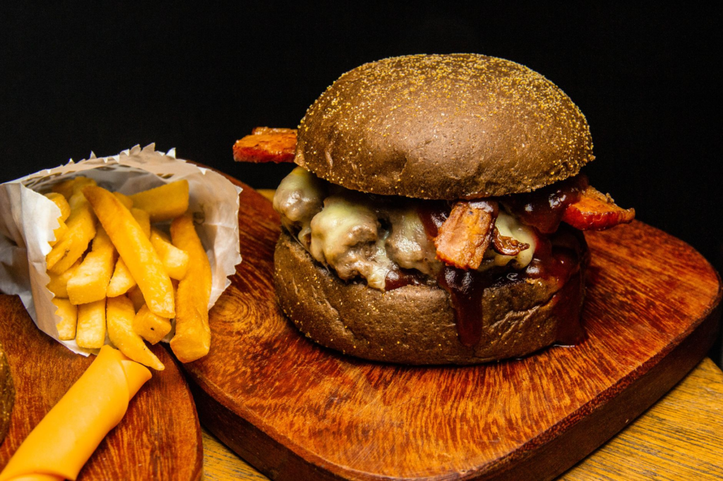 A BBQ bacon burger served with an amber ale on a rustic table. — burger beer pairings Las Vegas