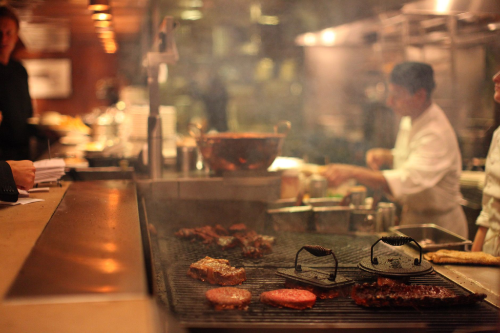 A chef grilling burgers in an open kitchen, showcasing the cooking process of the juiciest burgers Las Vegas Strip.